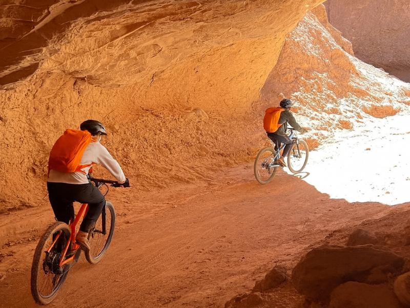 Mountain bikers riding into the narrow red rock walls of Garganta del Diablo canyon near San Pedro de Atacama