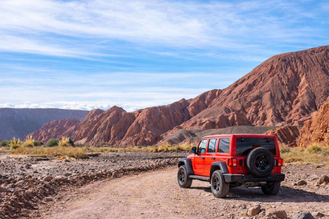 Guided Atacama Desert road trip during a tour with Atacama Chile Tours, featuring a red off-road Jeep on a scenic desert track
